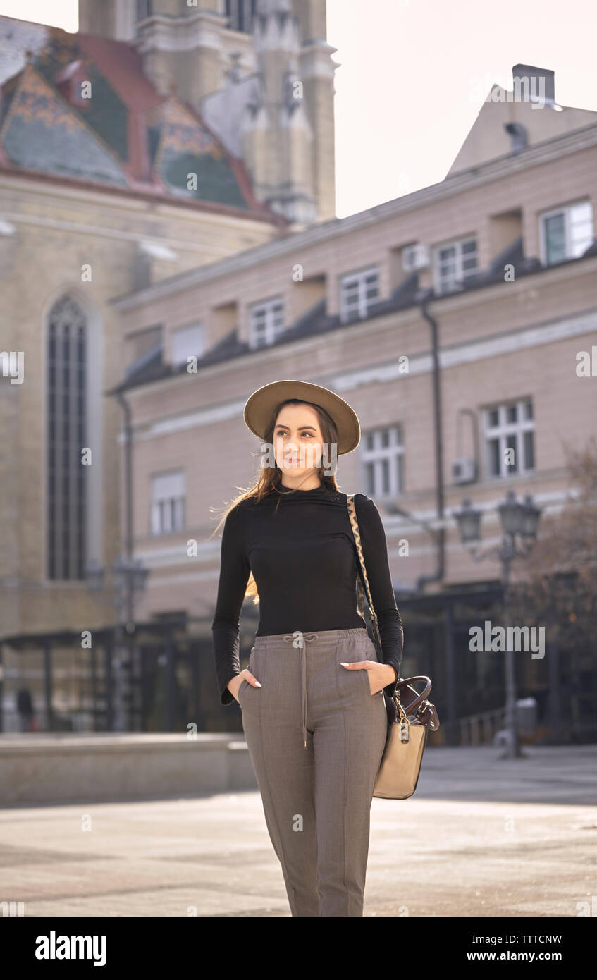 Frau mit Händen in den Taschen zu Fuß auf der Straße in der Stadt Stockfoto