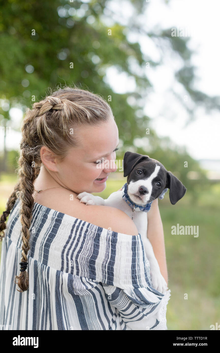 Mädchen mit Abholung Schwänze lächelnd an einen Hund mit schlappohren Stockfoto