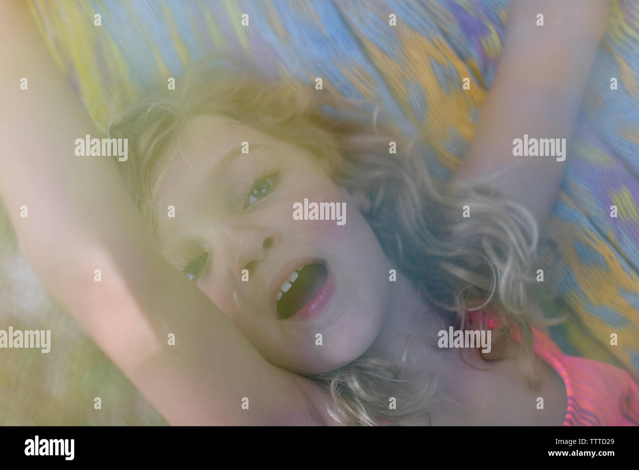 Mädchen mit lockigem Haar in einem farbenfrohen Hängematte Stockfoto