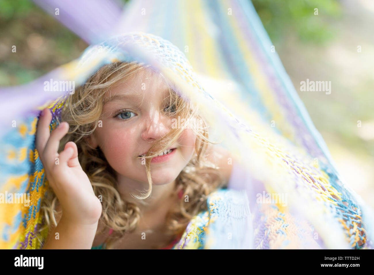 In der Nähe von einem kleinen Mädchen mit lockigem Haar in einem farbenfrohen Hängematte Stockfoto