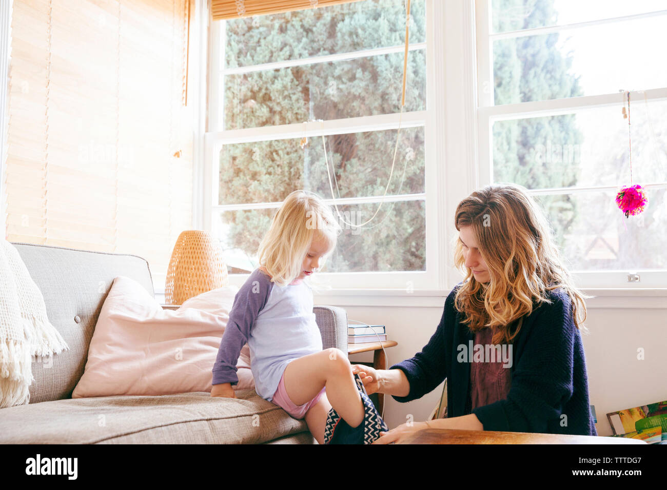 Mutter und Tochter, von Fenster zu Hause gekleidet Unterstützung Stockfoto