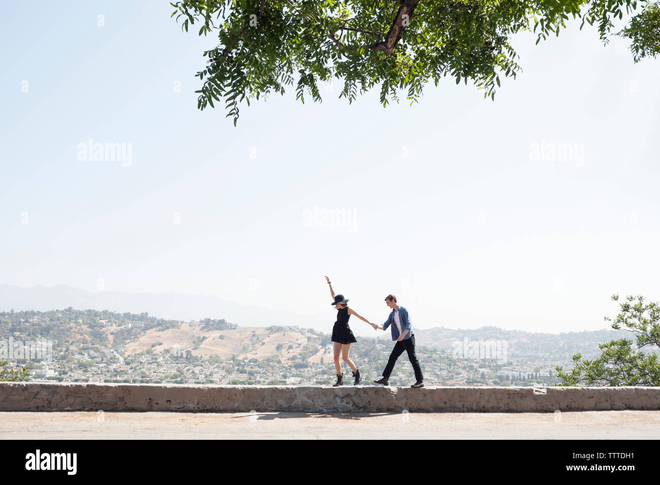 Junges Paar zu Fuß auf die Mauer gegen den klaren Himmel aufgeregt Stockfoto