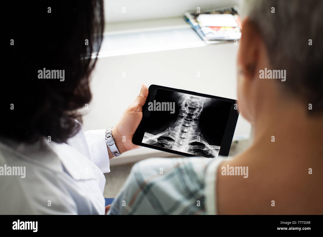 Frau Doktor X-ray Bild zeigen auf Tablet Computer zu Patient Stockfoto