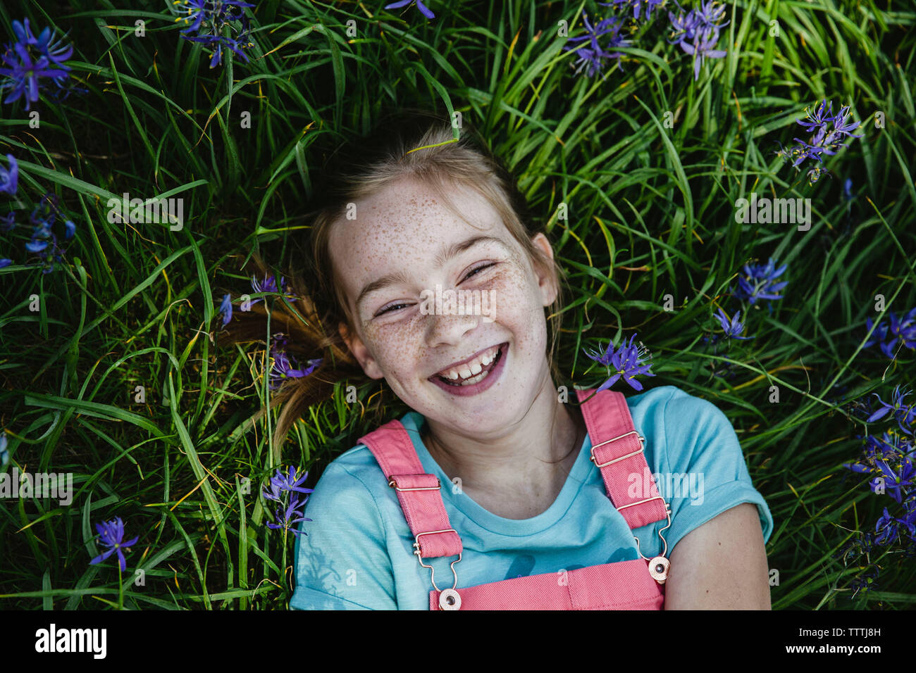 Vorderansicht des Mädchens mit Sommersprossen lächelnd in einem Feld von Blumen Stockfoto