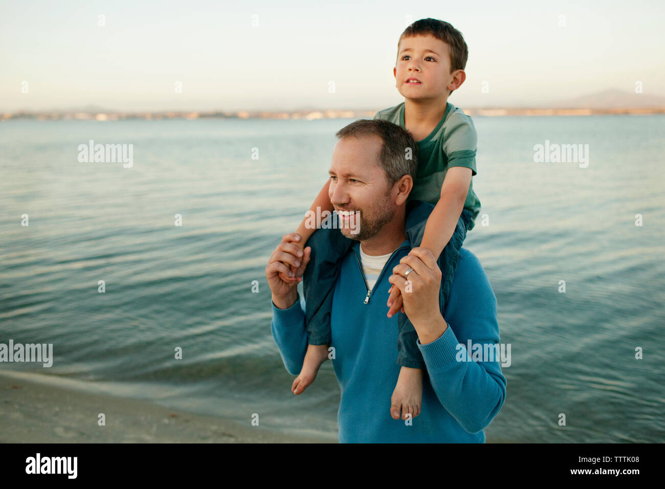 Vater mit Sohn auf Schultern am Strand Stockfoto