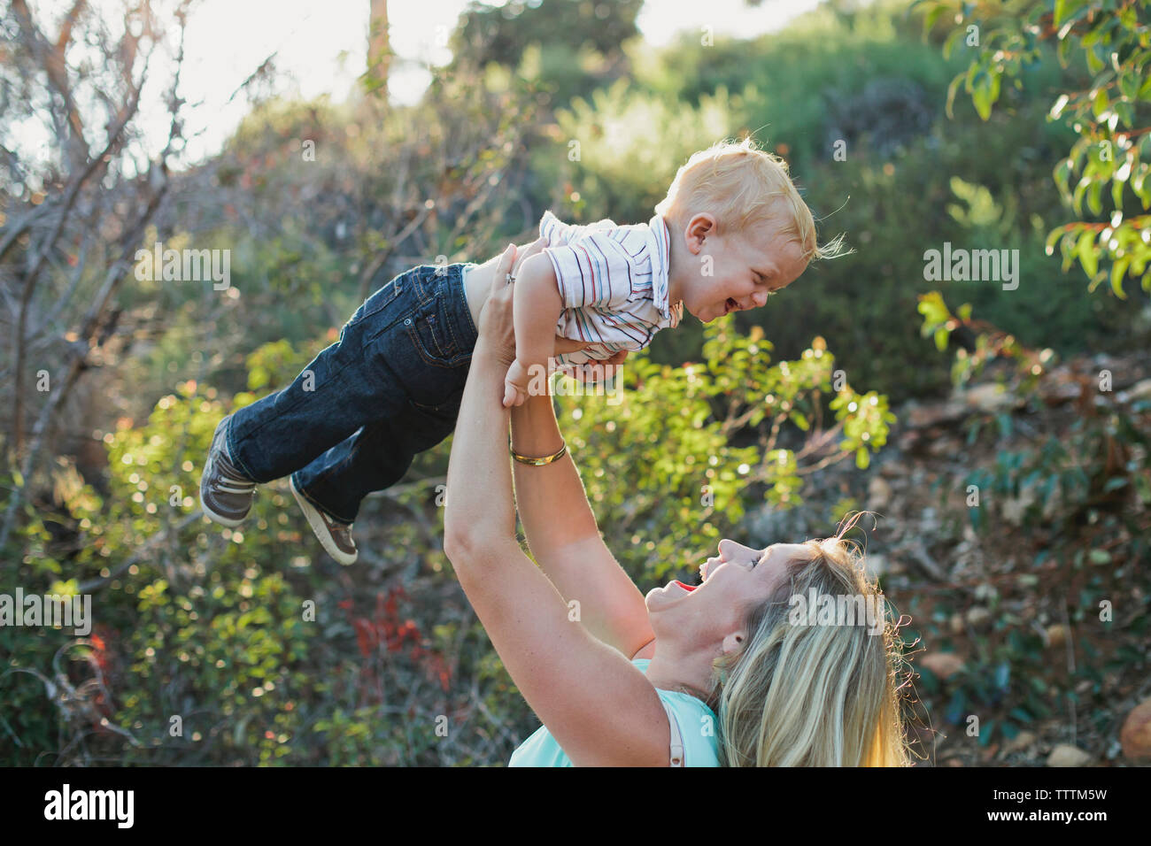 Seitenansicht des verspielten Mutter anheben Sohn beim Spielen im Park Stockfoto