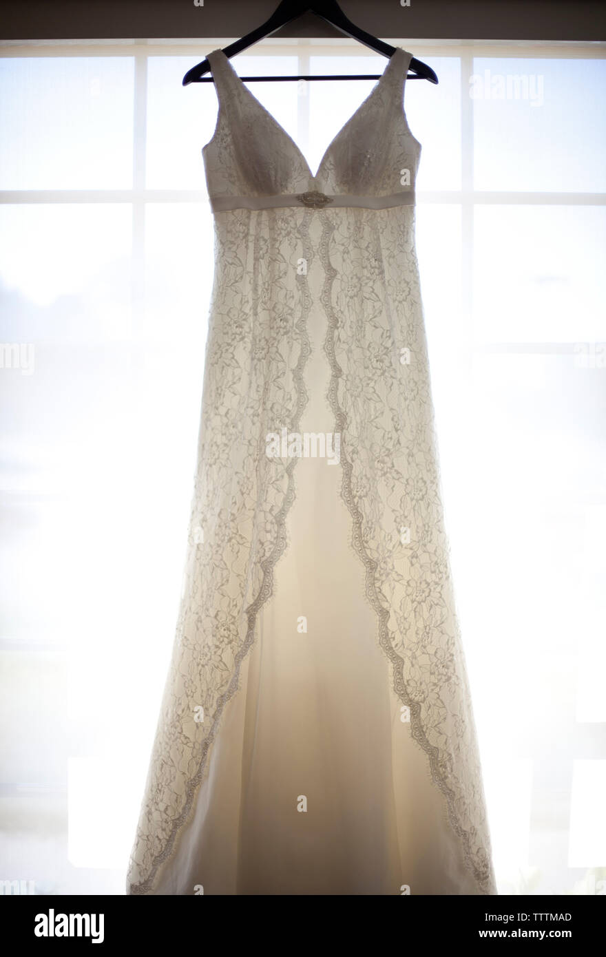 Hochzeitskleid hängt am Coathanger vor dem Fenster Stockfoto