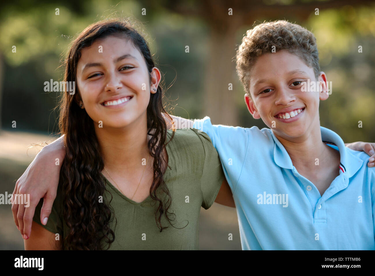 Portrait von fröhlichen Geschwister mit Arme um die Schultern im Park Stockfoto
