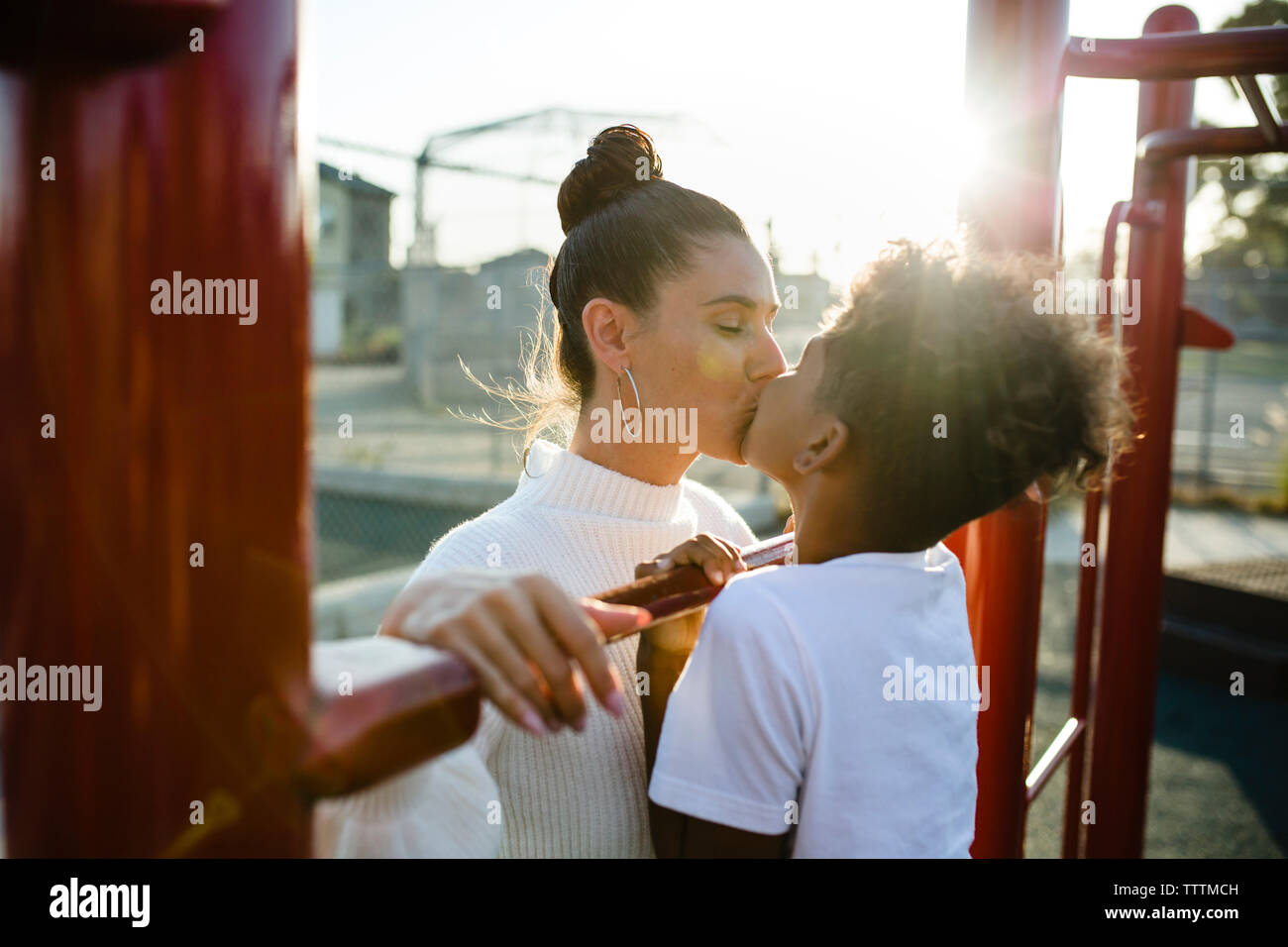 Liebevolle Mutter und Sohn Küssen auf den Mund am Spielplatz Stockfoto