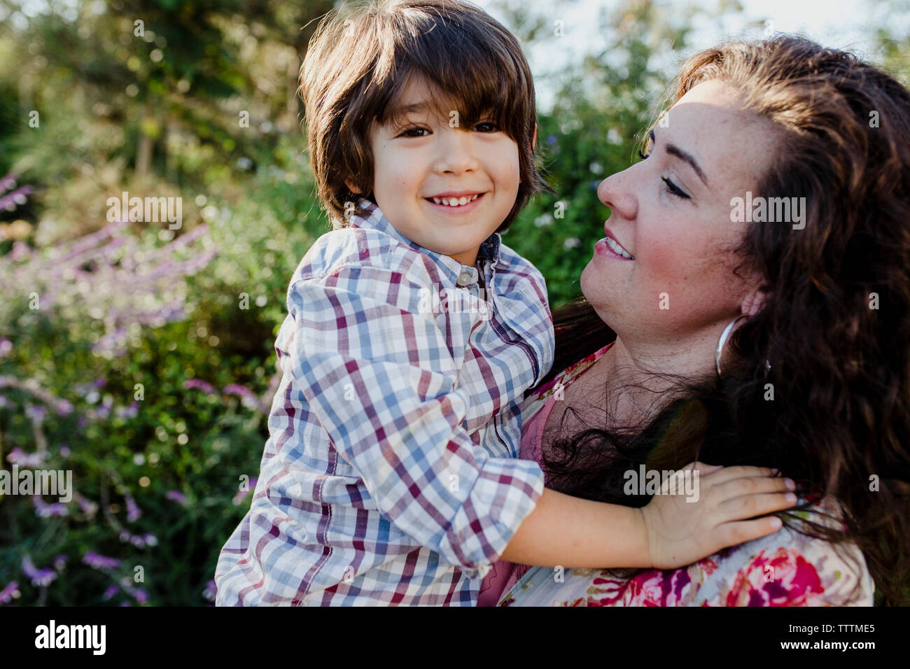Mutter mit Sohn beim Stehen gegen Pflanzen im Park Stockfoto