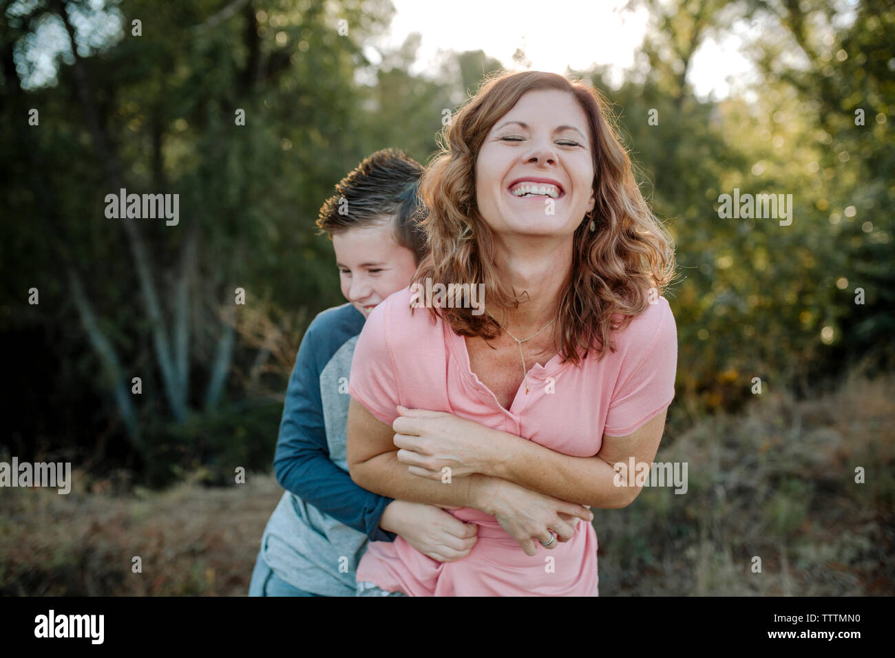 Happy Sohn kitzeln Mutter, während im Wald Stockfoto