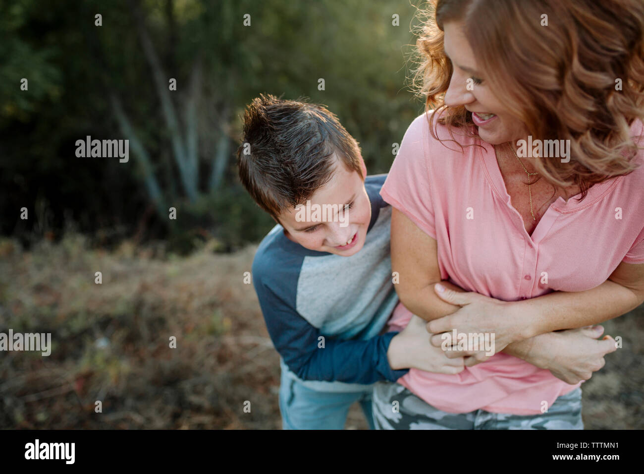 Happy Sohn kitzeln Mutter, während im Wald Stockfoto