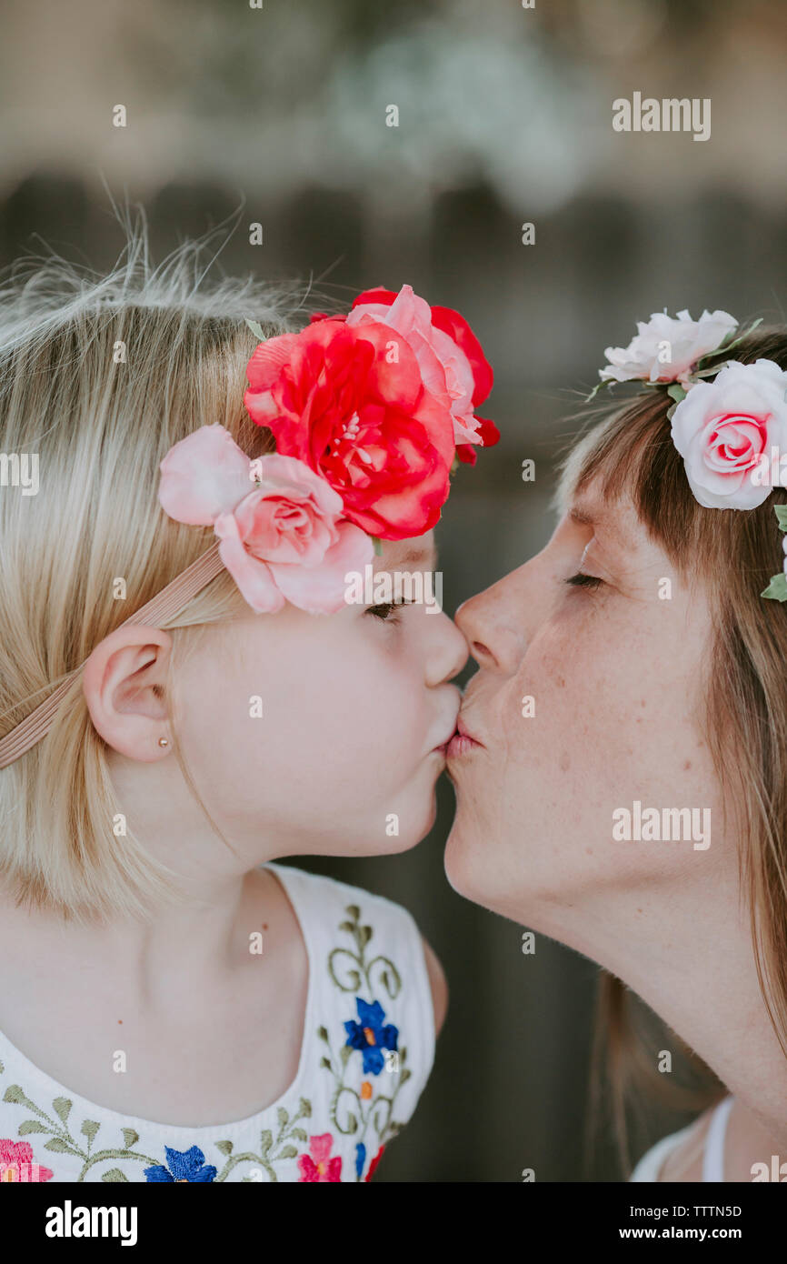 Nahaufnahme der Mutter und niedlichen Tochter tragen Diademe in Yard küssen Stockfoto