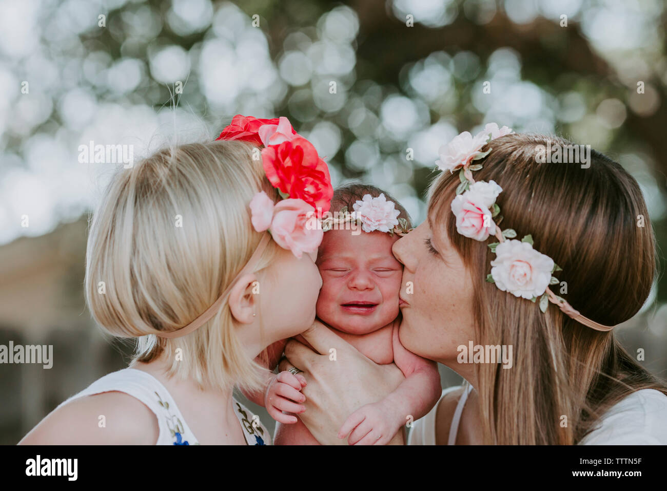 Mutter und Tochter küssen Süßes neugeborenes Mädchen im Hof Stockfoto
