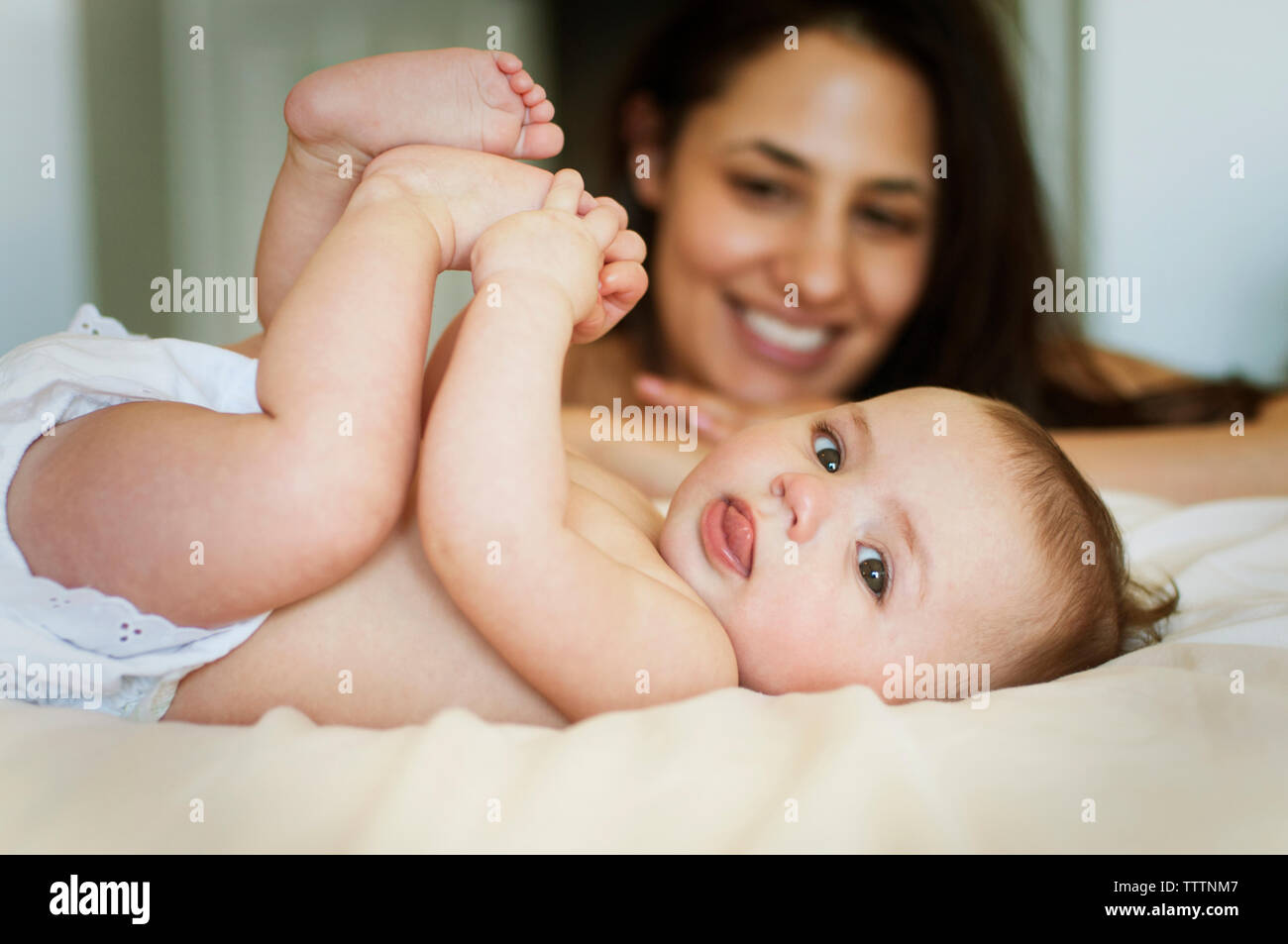 Glückliche Mutter beobachten verspielte Baby im Bett Stockfoto