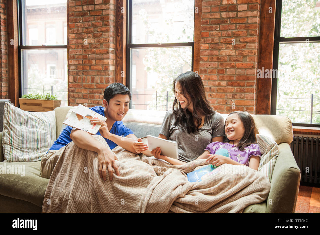Mädchen zeigen Tablet Computer Eltern beim Sitzen auf dem Sofa zu Hause Stockfoto
