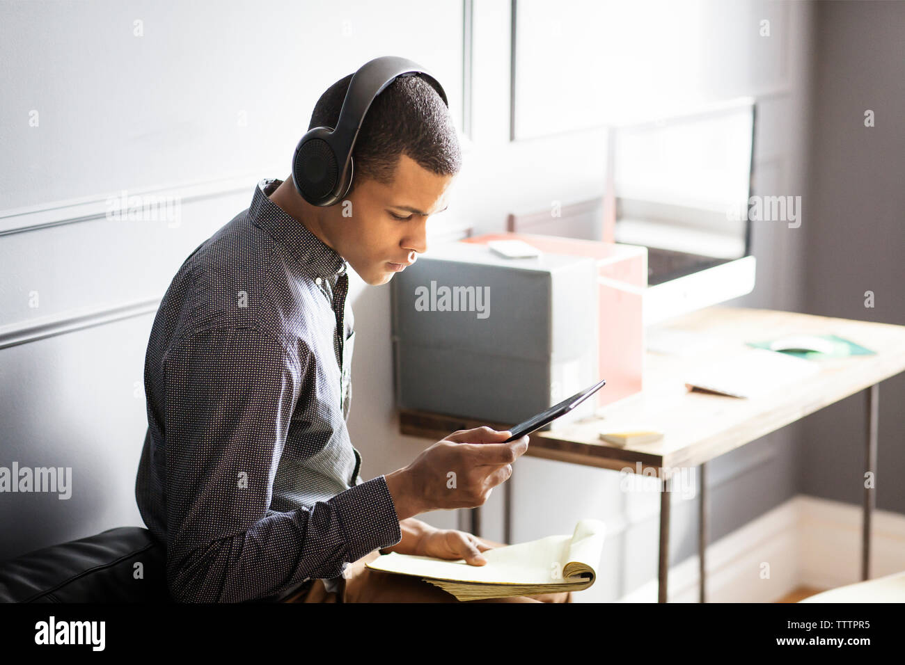 Seitenansicht des geschäftsmannes Musik hören, während Sie Tablet Computer im Büro Stockfoto