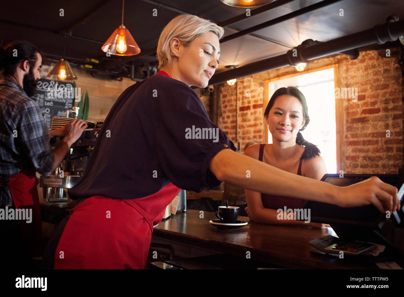 Frau Suchen an Eigentümer mit Maschine bei Cash Counter Stockfoto