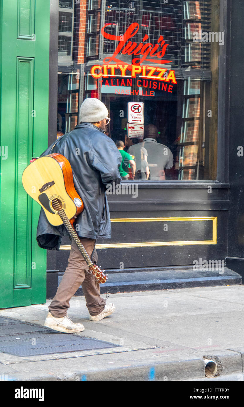 Gaukler mit einer akustischen Gitarre vorbei gehen. Luigi's City Pizza restaurant am 3. Ave Nashville Tennessee USA. Stockfoto