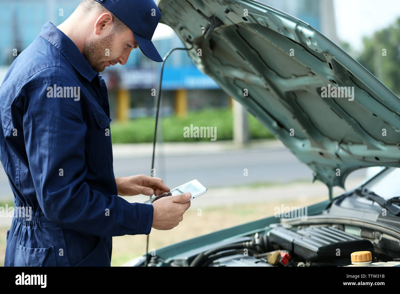 Mechaniker vor einem offenen Wagen Haube mit dem Tablet Stockfoto