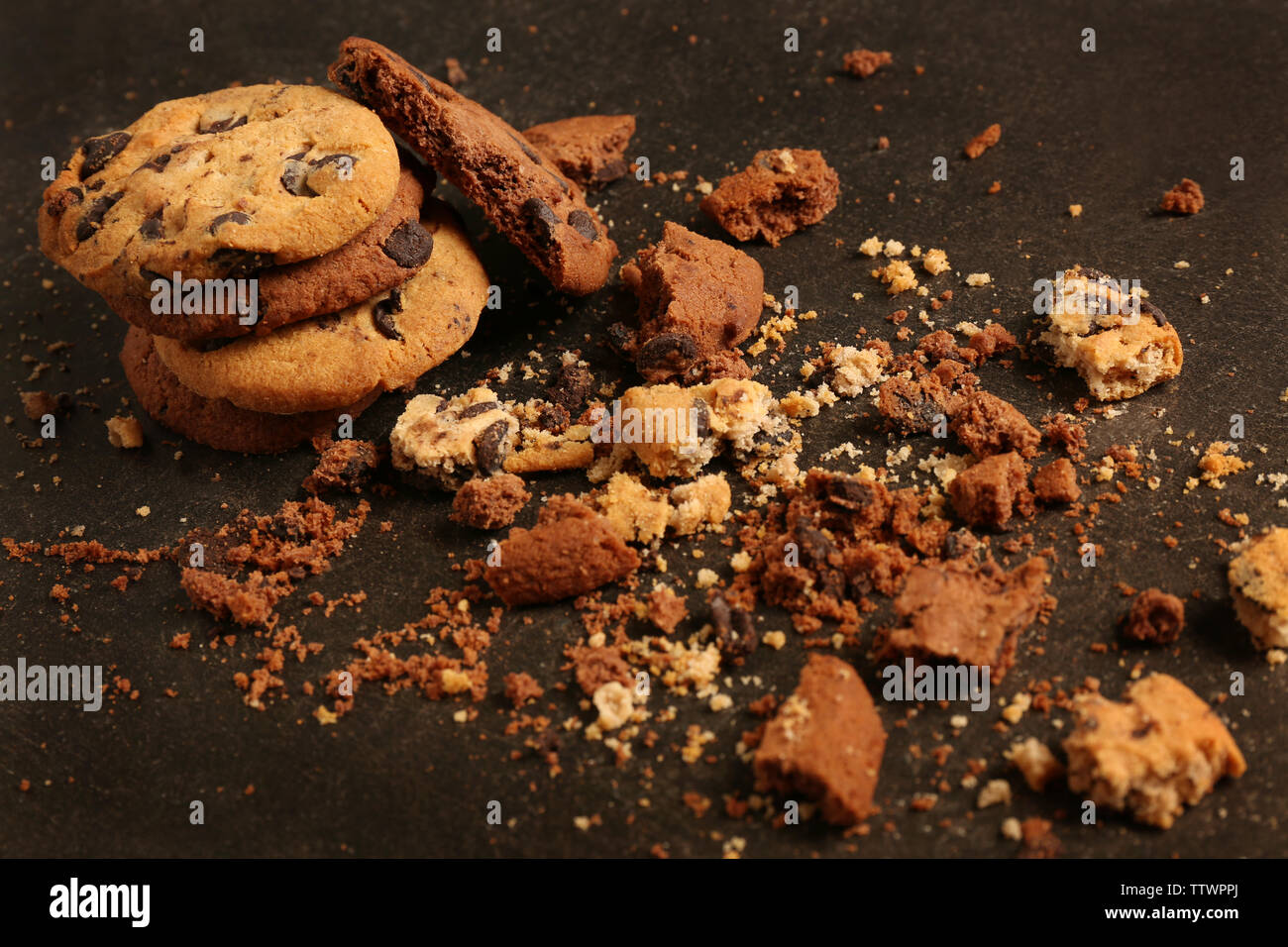 Leckere Cookies mit Schokoladenstückchen und Krümel auf dunklem Hintergrund Stockfoto