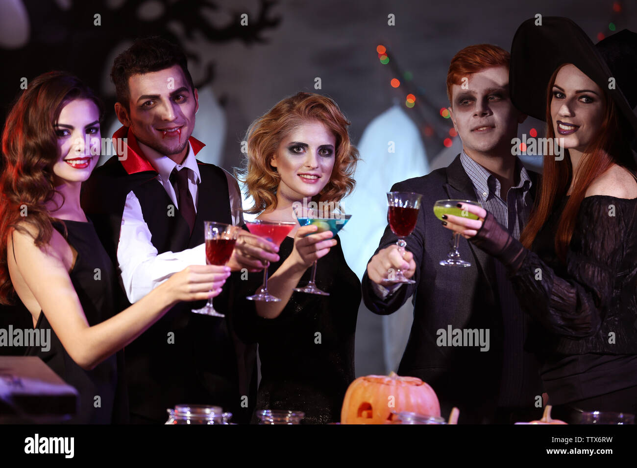 Junge Leute in Kostümen trinken Cocktails an Halloween Party Stockfoto