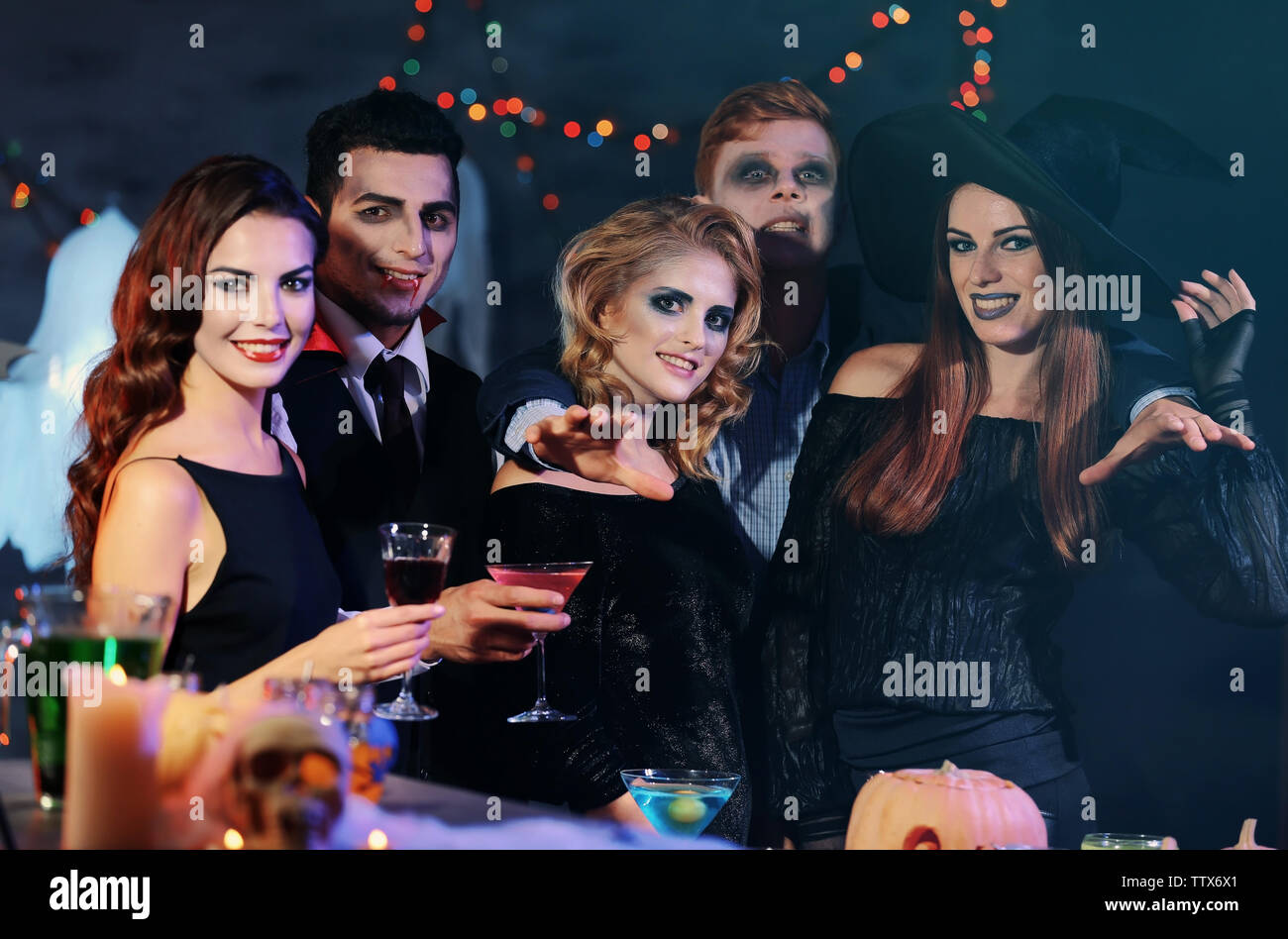 Junge Leute in Kostümen trinken Cocktails an Halloween Party Stockfoto