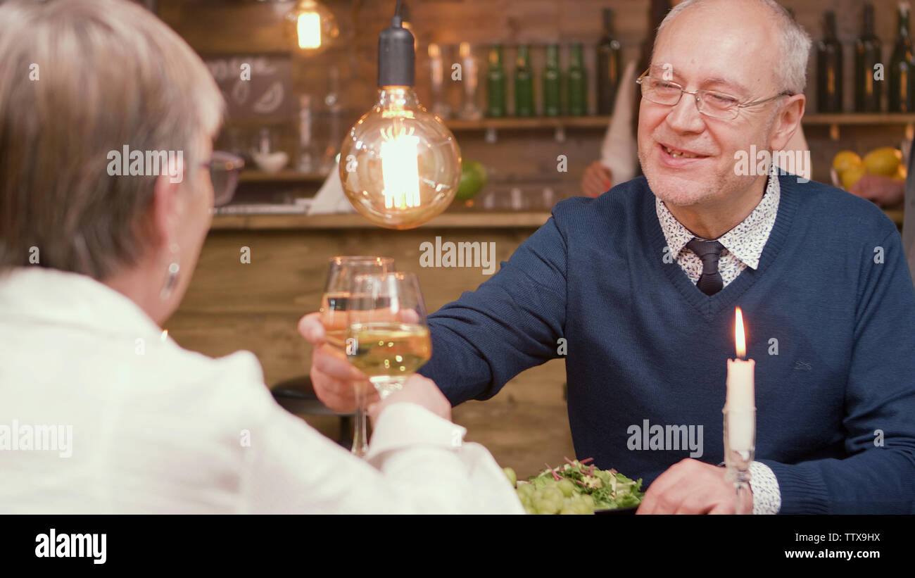 Schöne ältere Paare, Toast und Anstoßen. Das Essen im Restaurant. Mann und Frau in den 60er Jahren. Stockfoto