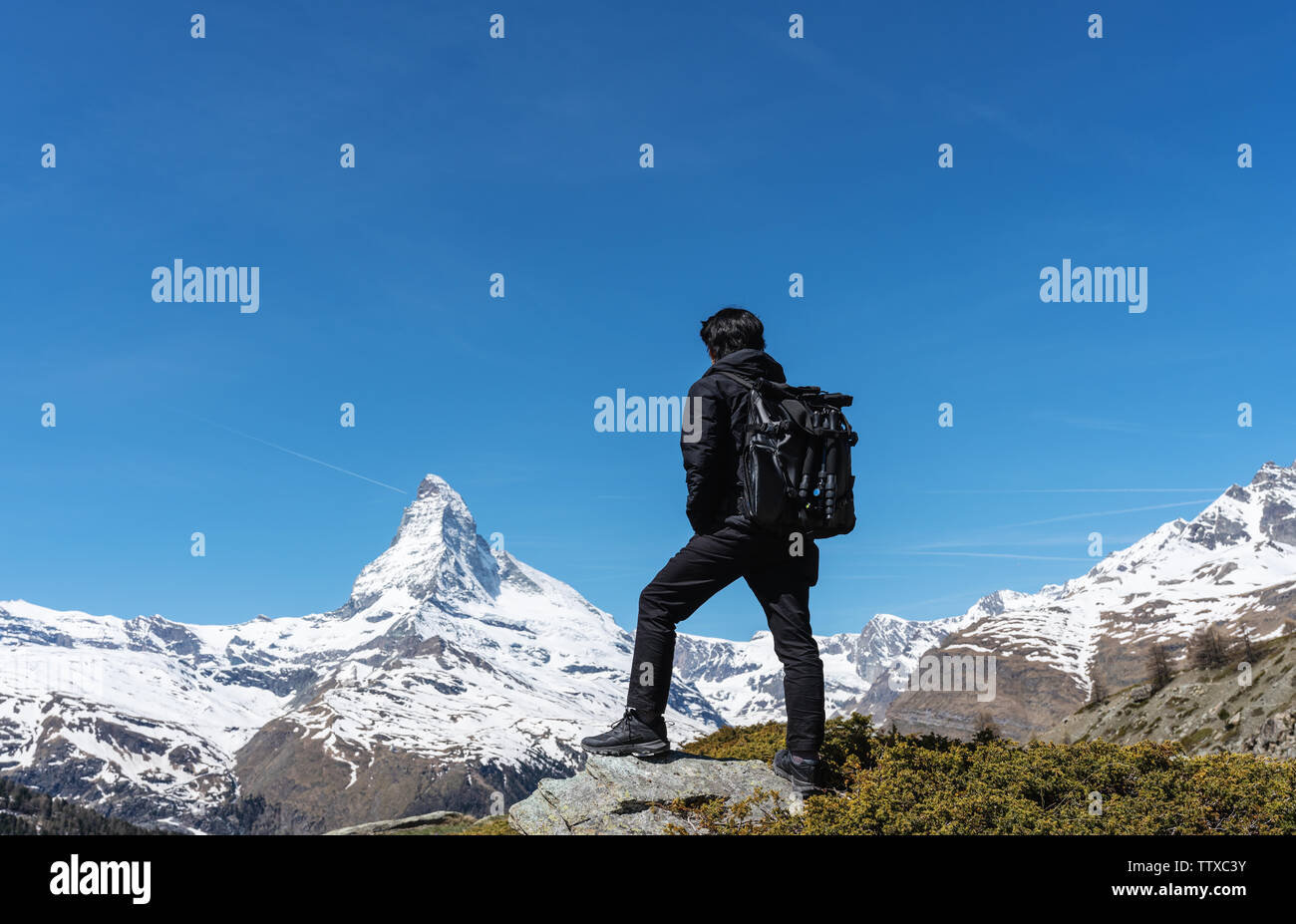 Reisen in der Schweiz, ein Mann mit Rucksack auf den Felsen am Matterhorn View suchen. Trekking in Zermatt, Schweiz Stockfoto