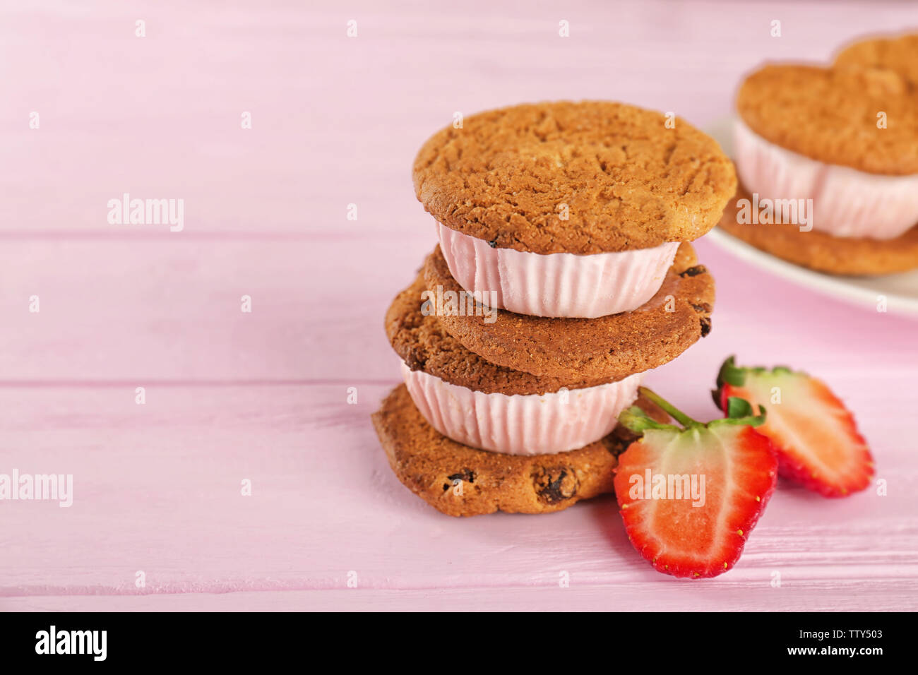 Eis cookie Sandwiches mit frischen Erdbeeren auf rosa Holz- Hintergrund Stockfoto