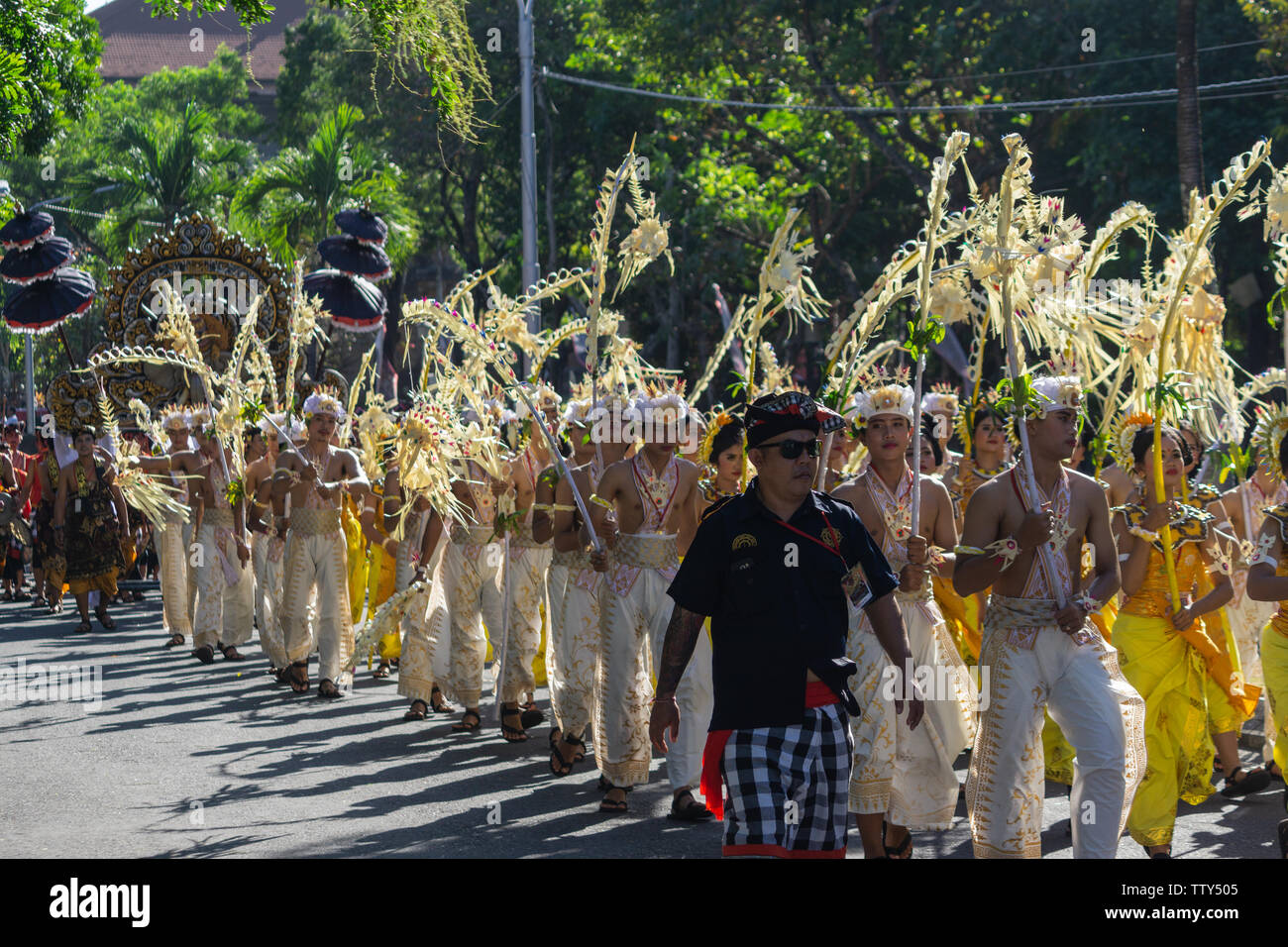DENPASAR/BALI - 15. JUNI 2019: Sampian Tänzerin, die in gelben und weissen Tracht, Wandern im Bali Arts Festival 2019 durchzuführen. Sie verwenden die Palm Stockfoto