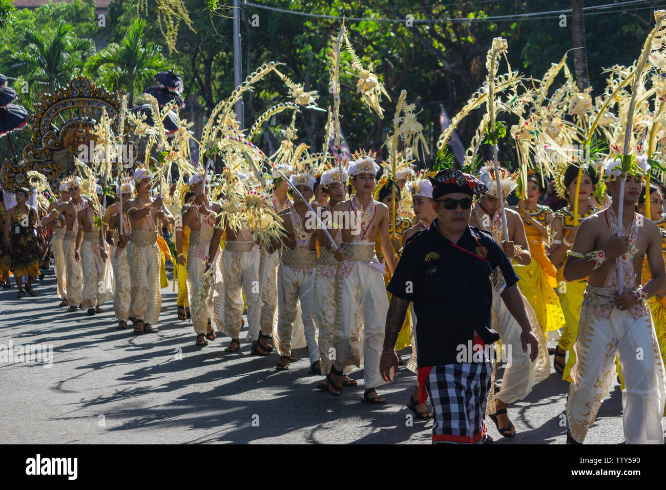 DENPASAR/BALI - 15. JUNI 2019: Sampian Tänzerin, die in gelben und weissen Tracht, Wandern im Bali Arts Festival 2019 durchzuführen. Sie verwenden die Palm Stockfoto