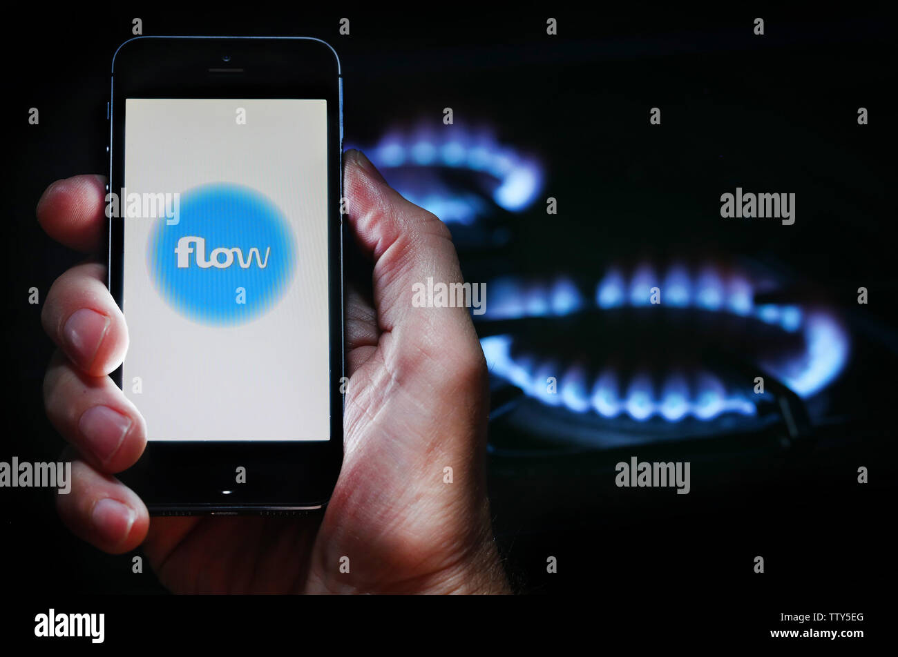 Ein Mann auf der Website Logo auf der Suche nach Energie unternehmen Energie fließen auf seinem Mobiltelefon vor seinem Gaskocher (Editorial nur verwenden) Stockfoto