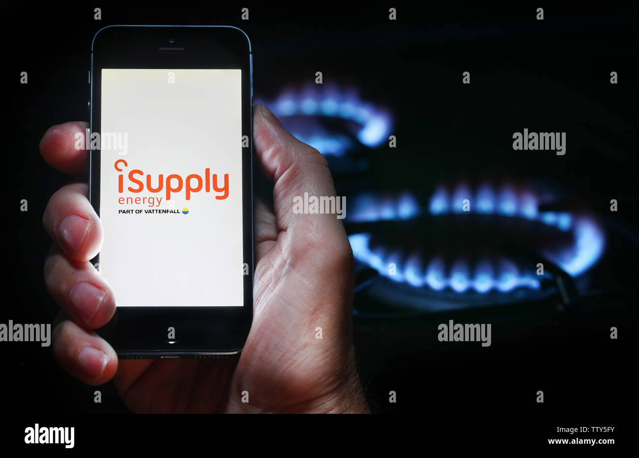 Ein Mann auf der Suche auf der Website Logo für Energieunternehmen iSupplyEnergy auf seinem Mobiltelefon vor seinem Gaskocher (Editorial nur verwenden) Stockfoto