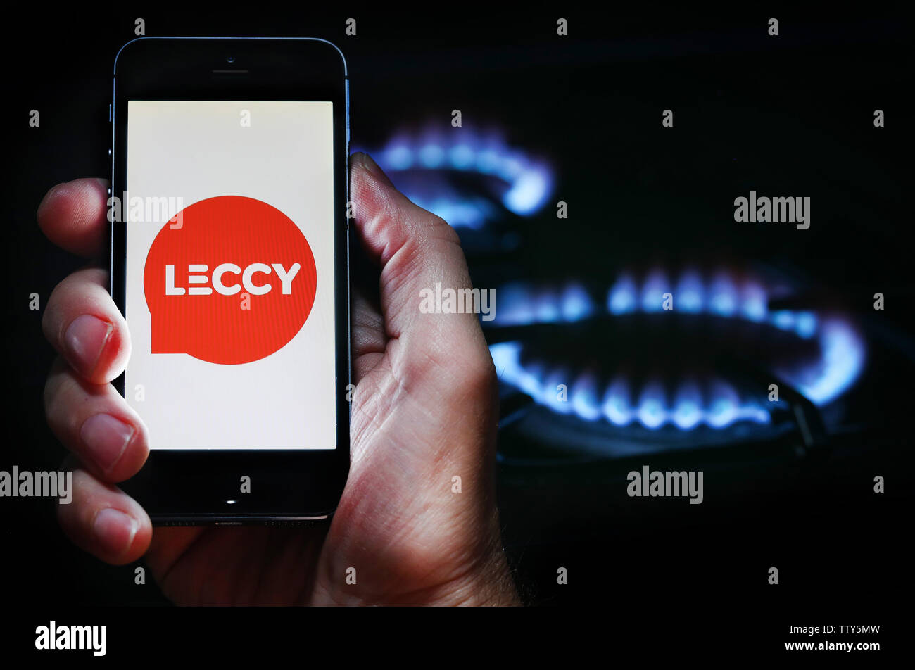 Ein Mann auf der Website Logo auf der Suche nach Energie unternehmen Energie Leccy auf seinem Mobiltelefon vor seinem Gaskocher (Editorial nur verwenden) Stockfoto