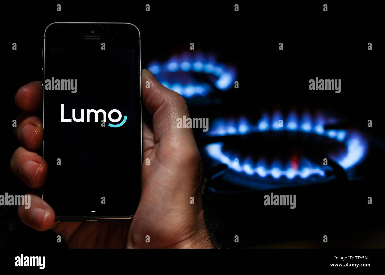 Ein Mann auf der Website Logo auf der Suche nach Energie unternehmen Lumo Energie auf seinem Mobiltelefon vor seinem Gaskocher (Editorial nur verwenden) Stockfoto
