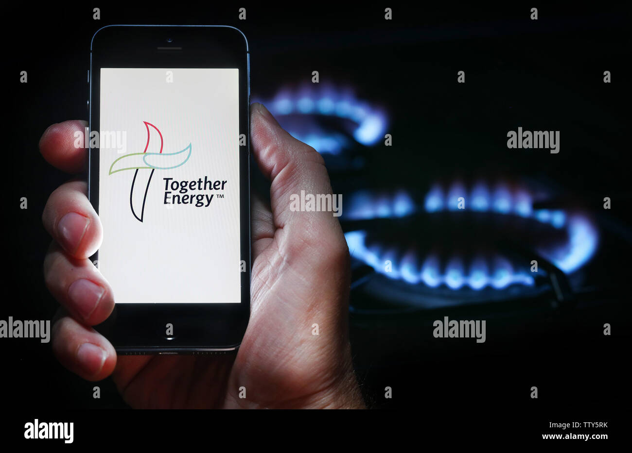 Ein Mann auf der Website Logo für Energie unternehmen Energie auf seinem Mobiltelefon vor seinem Gasherd nur (Redaktionelle Nutzung) Stockfoto
