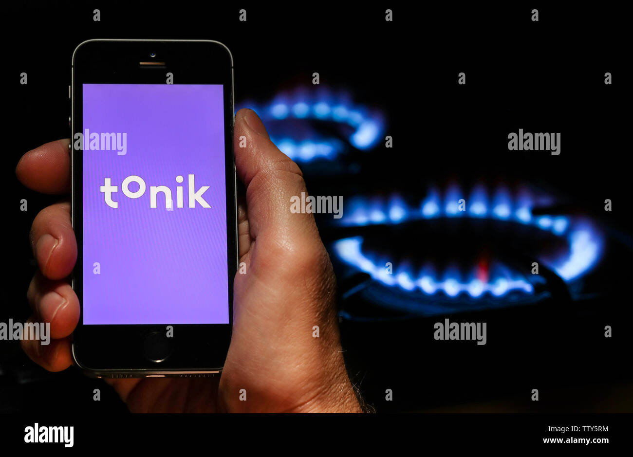 Ein Mann auf der Website Logo auf der Suche nach Energie unternehmen Tonik auf seinem Mobiltelefon vor seinem Gaskocher (Editorial nur verwenden) Stockfoto