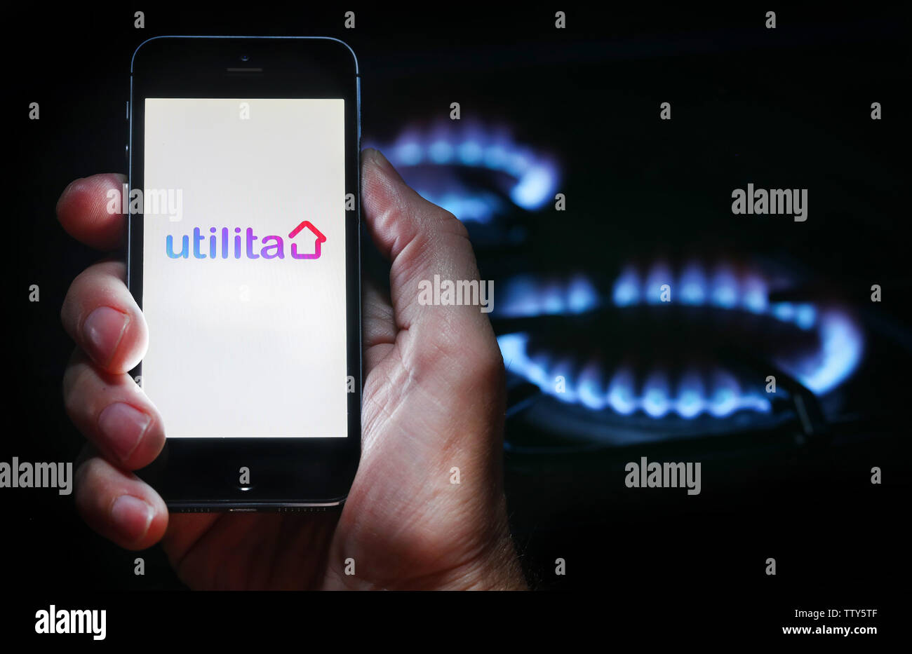 Ein Mann auf der Website Logo auf der Suche nach Energie Firma Utilita auf seinem Mobiltelefon vor seinem Gaskocher (Editorial nur verwenden) Stockfoto