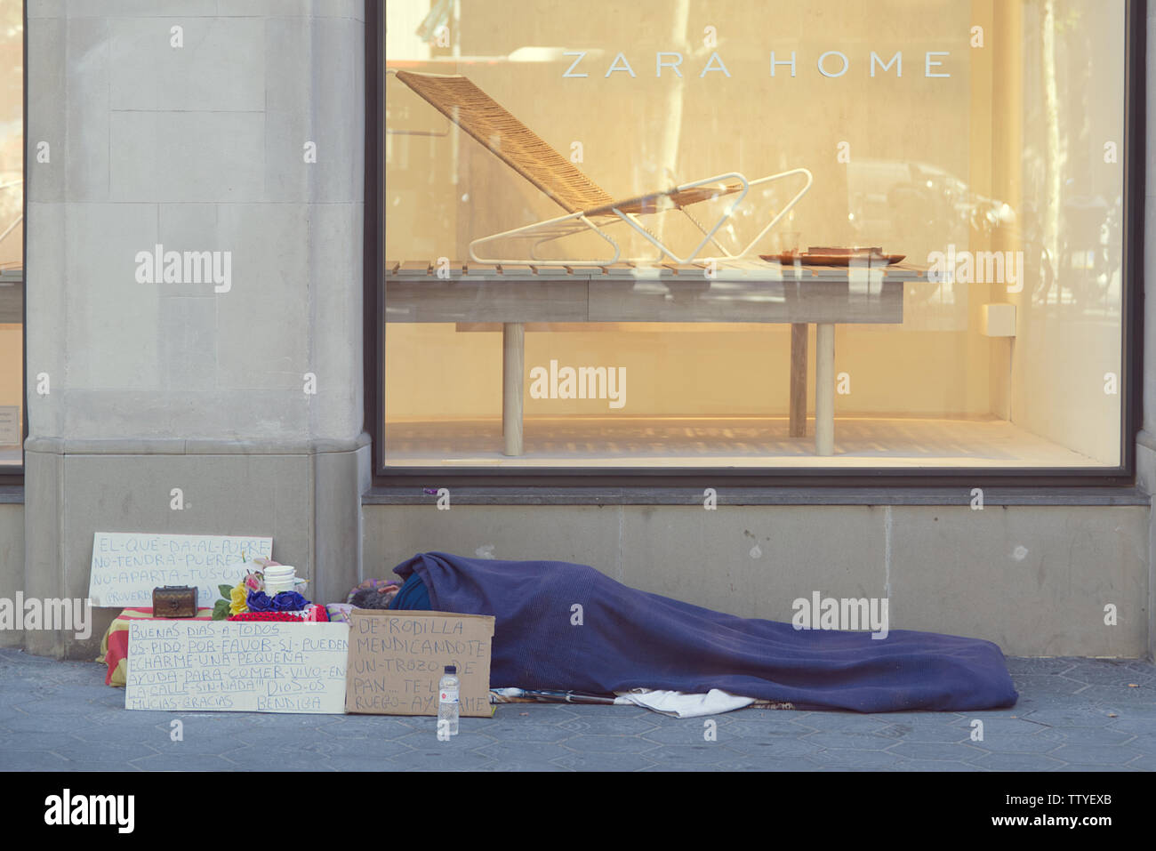 BARCELONA, 18. JUNI 2019: Obdachlose auf der Straße zu schlafen vor einem Zara Home Schaufenster in Paseig de Gracia, Barcelona Stockfoto