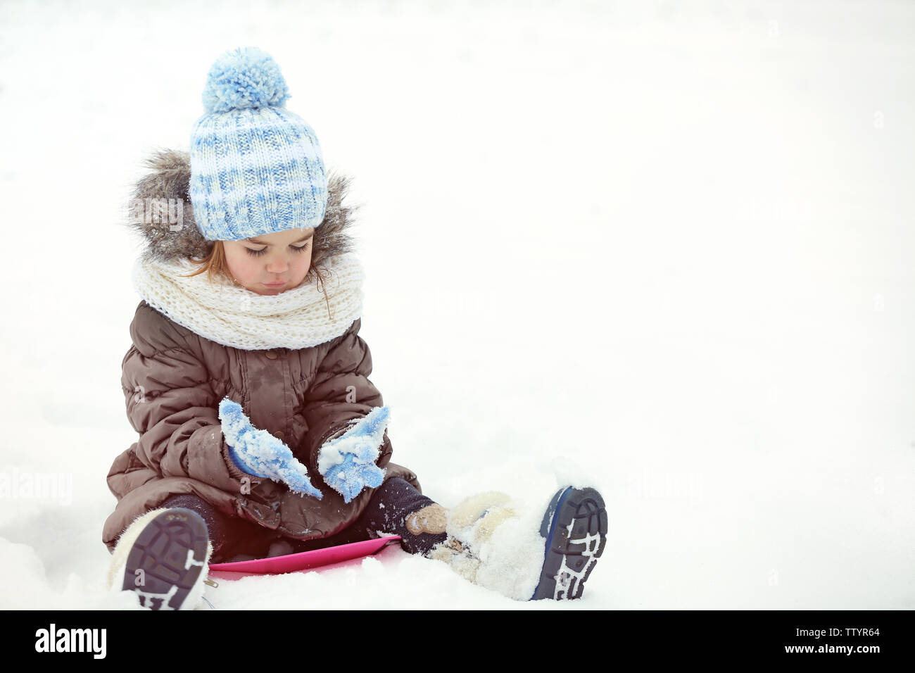 Süße kleine Mädchen mit Untertasse Schlitten im Freien auf Winter Tag Stockfoto