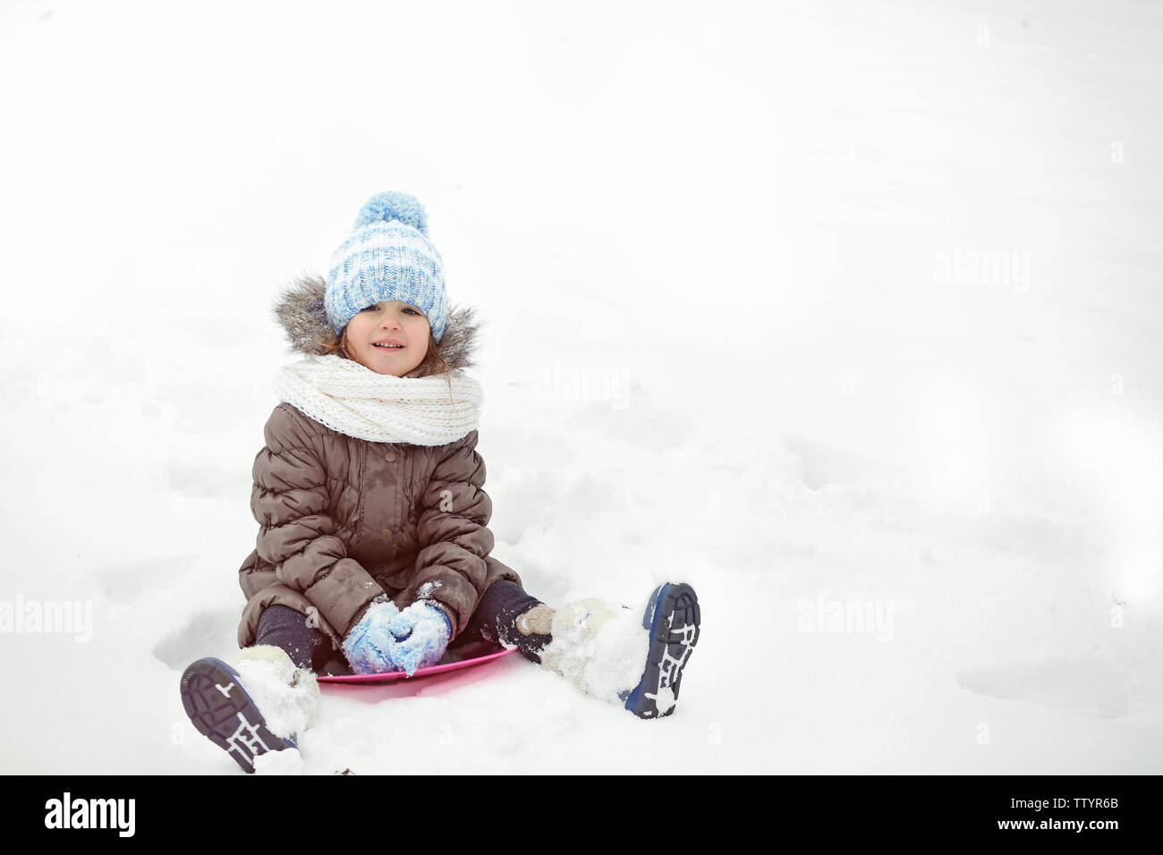 Süße kleine Mädchen mit Untertasse Schlitten im Freien auf Winter Tag Stockfoto
