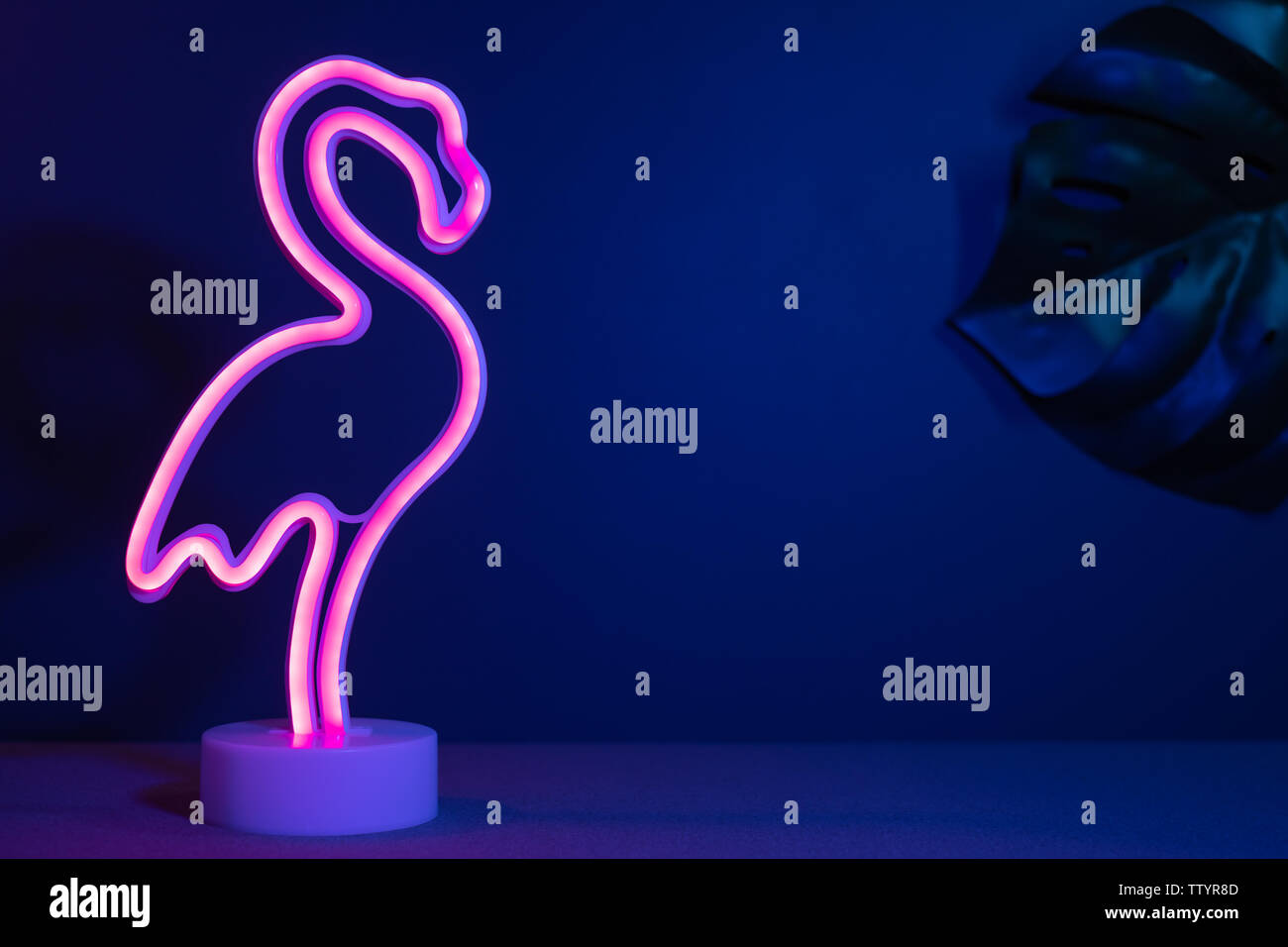 Sommer rosa Flamingo und monstera Blatt mit neon pink und blau Licht. Ferienhäuser Hintergrund Stockfoto