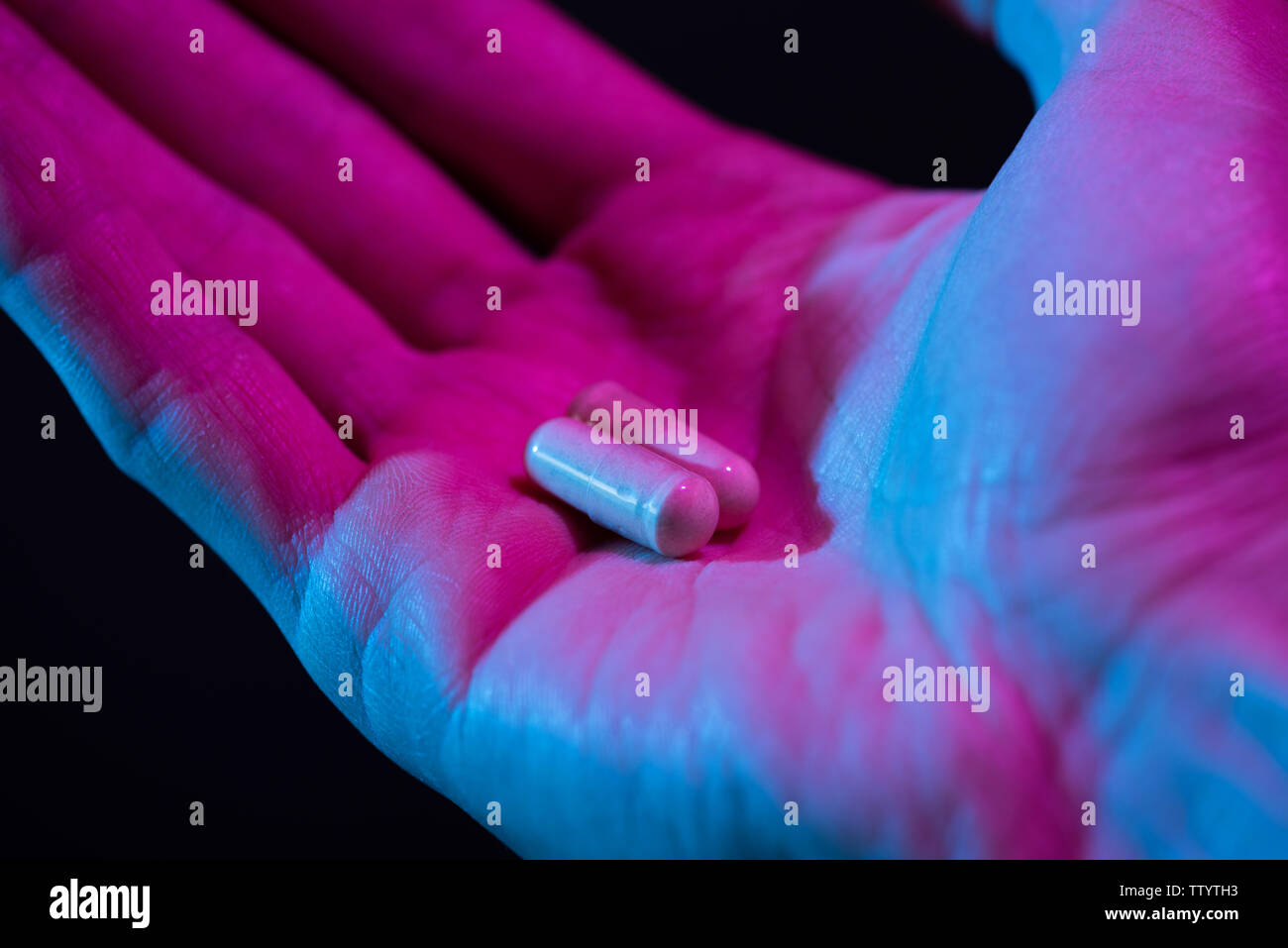 Zwei Pillen in der hand Nahaufnahme auf dunklem Hintergrund. Drogen Tablet in der Palme. Stockfoto