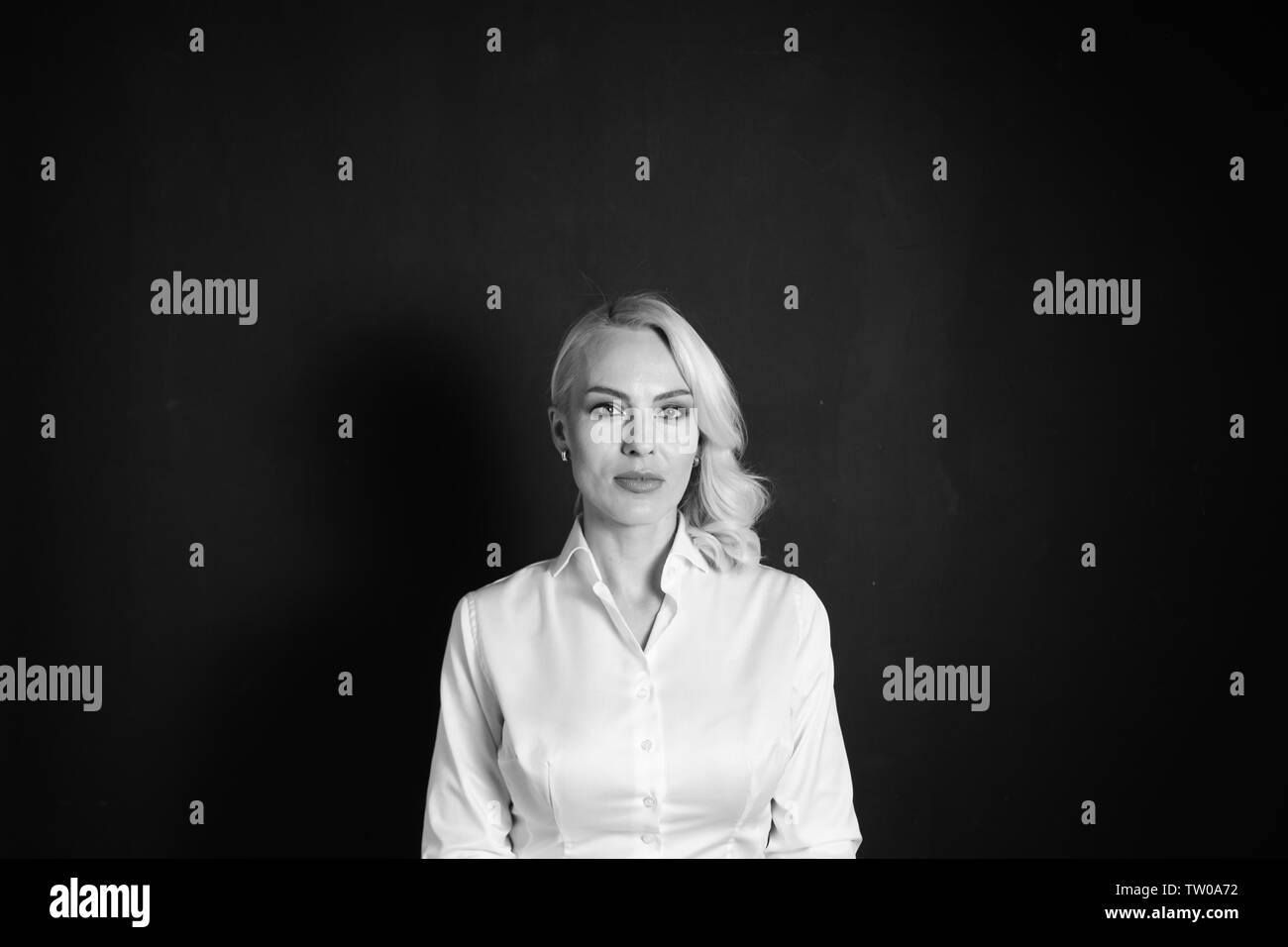 Studio Portrait von eine schöne blonde Frau in einem weißen Hemd gegen Schwarze einfachen Hintergrund Stockfoto