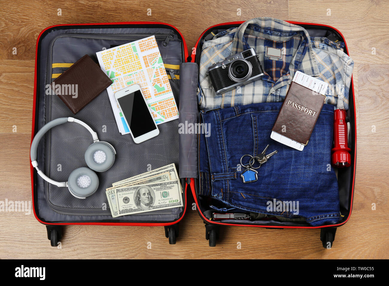 Gepackte Koffer mit Zubehör auf hölzernen Hintergrund Stockfoto