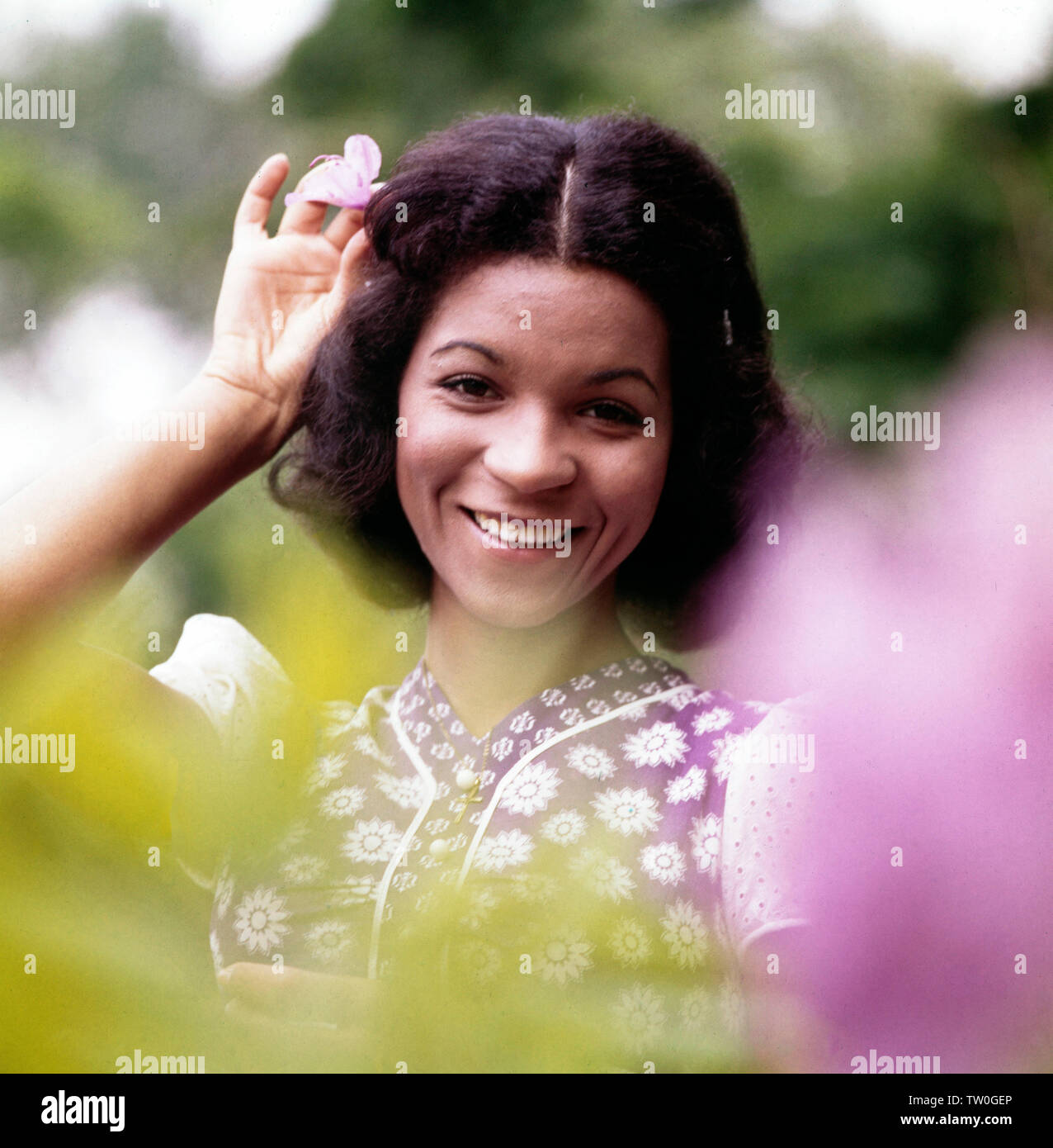 Porträt der deutschen Schlager - Disco- und Popsängerin Ramona Wulf hinter verschwommenen Blumen, Deutschland Ca. 1972. Porträt des deutschen Pop, Disco und Pop Sängerin Ramona Wulf hinter unscharfe Blumen, Deutschland Ca. 1972. Stockfoto