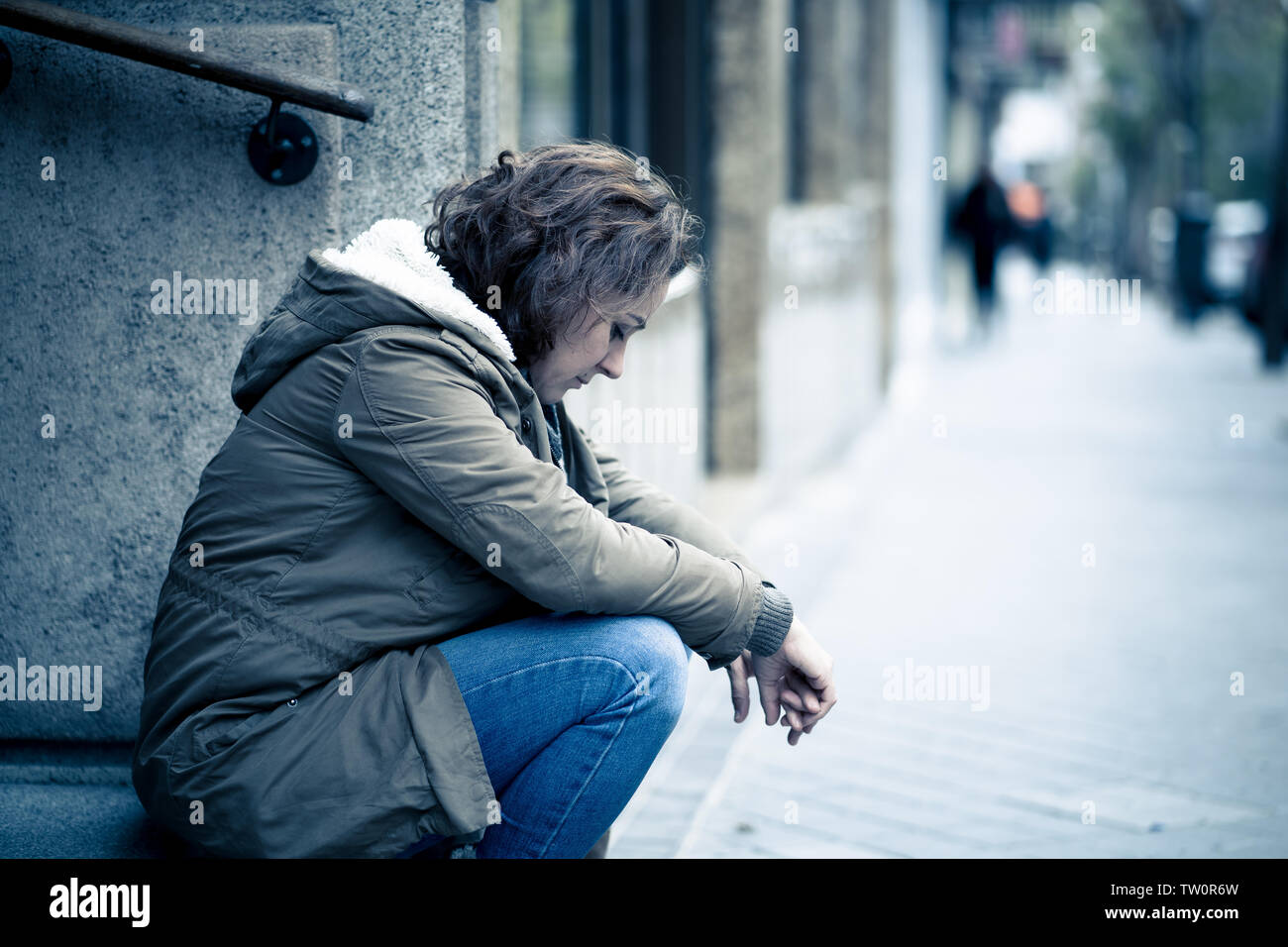 Attraktive Frau, die unter Depressionen leiden Holzeinschlag untröstlich traurig, unglücklich und einsam sitzen in Stadt Urban Street in der psychischen Gesundheit emotionalen Schmerz Abu Stockfoto