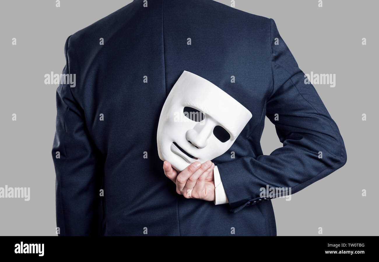 Business Betrugsbekämpfung Konzept. Geschäftsmann die Maske in der Hand hinter seinem Rücken zu verstecken. Stockfoto