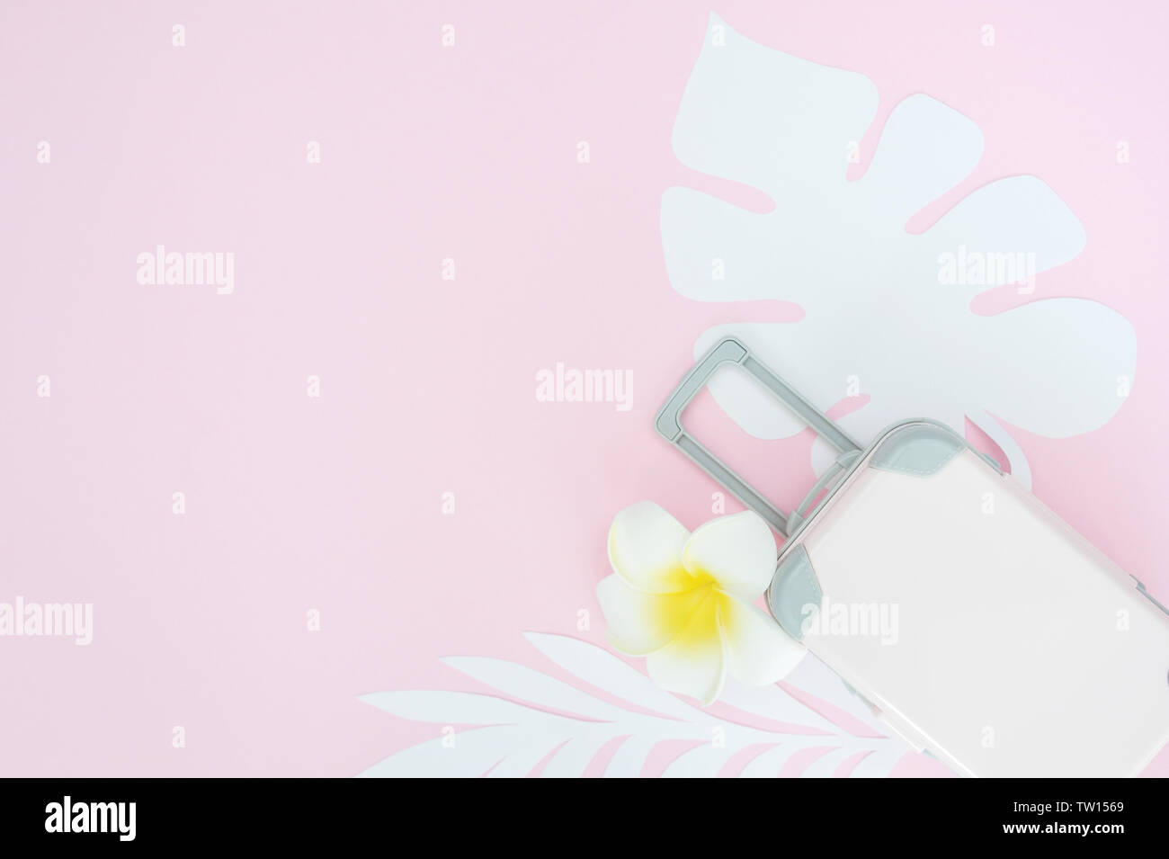 Rosa Reisekoffer auf rosa Hintergrund mit tropischen Blättern und weissen Blüten. Konzept für Reisen. Flach Stockfoto Rosa Reisekoffer auf rosa Hintergrund mit tropischen Blättern und weissen Blüten. Konzept für Reisen. Flach Stockfoto